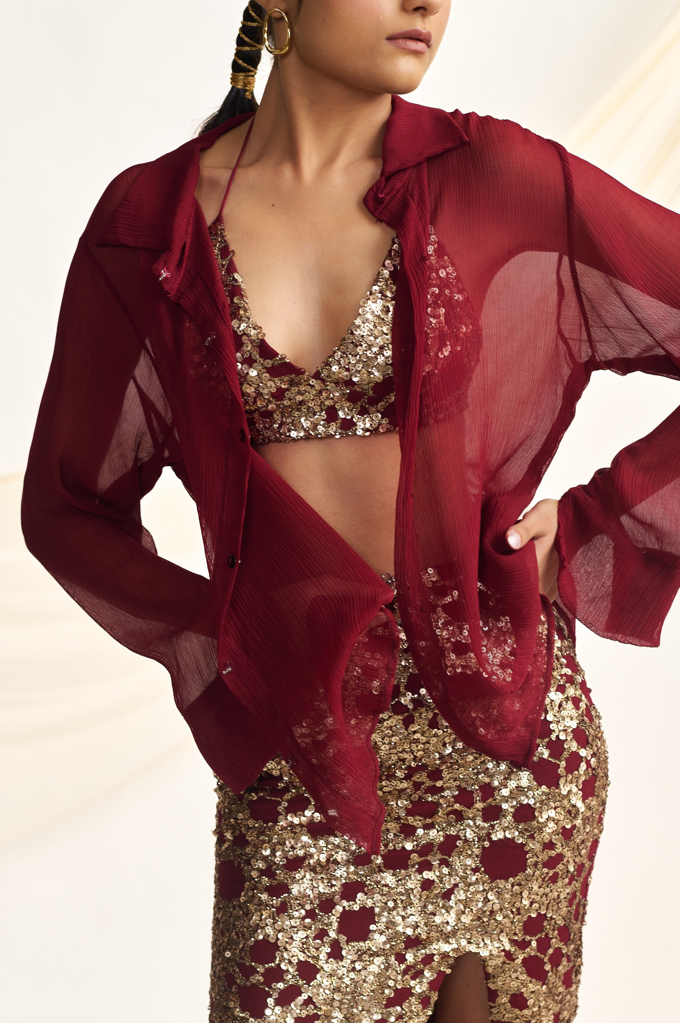 Woman wearing a red and gold outfit with a sheer red jacket on a white background